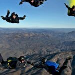 An image of people with a black suit and bags experiencing exciting skydiving in Pattaya.