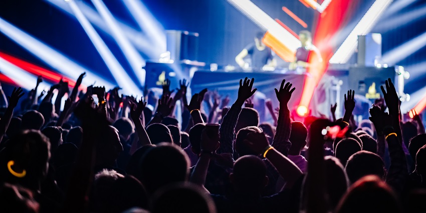 View of people dancing to dj's beats under vibrant neon lights