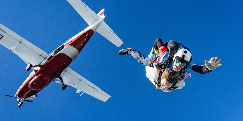 Image of a white and red aeroplane soaring through a clear blue sky on a sunny day.