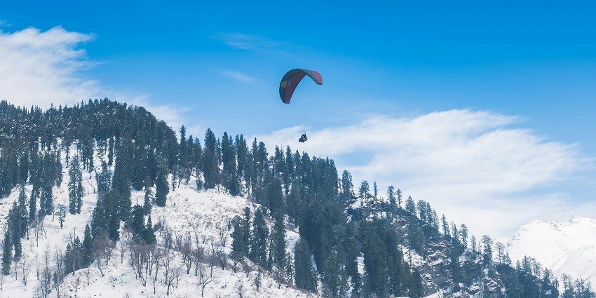 A person gliding high in Solang Valley, one of the serene spots for paragliding in Manali.