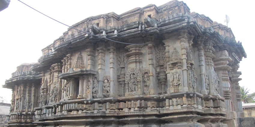 A picture of a historical temple sanctum with intricate carvings on its exterior stone walls