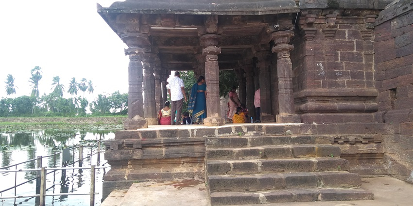 A picture of a historical temple in East Godavari with a tranquil water body flowing next to it