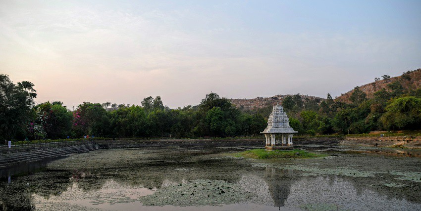 Lakeside view of the Sri Kalahasti, nestled amidst lush greenery and verdant hills