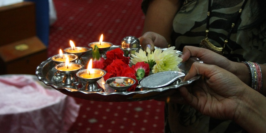 Image of pooja thali decorated with flowers and diyas - devotees holding the thali