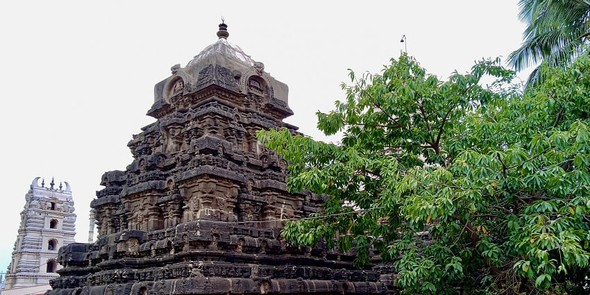 Image of temple surrounded by lush green trees under clear blue sky in a day time