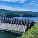 A stunning view of the massive dam surrounded by lush greenery and hills.