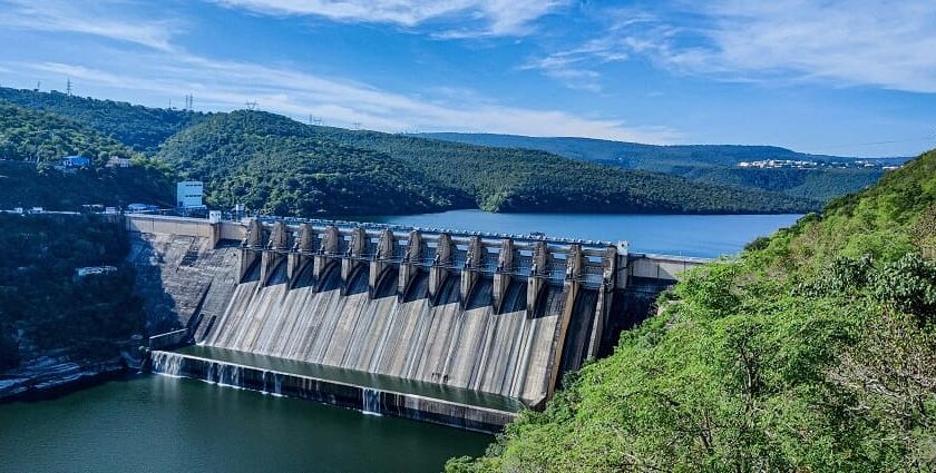 A stunning view of the massive dam surrounded by lush greenery and hills.