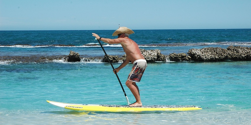 A person standing on a paddleboard and rowing in the middle of a sea