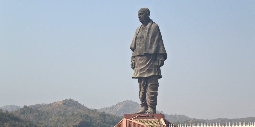 An expansive view of the statue of Unity, with the backdrop of green hills.