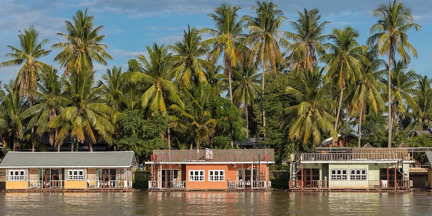 A picture of a floating bungalow in Cambodia with beautiful pine trees in the background
