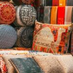 A view of cushions and pillows made up of raw silk and adorned with intricate designs.