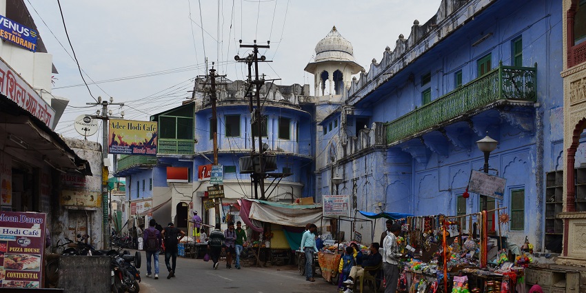 A lively scene at Pushkar Market in Rajasthan with vendors selling vibrant textiles, traditional garments, jewellery, and handcrafted goods.