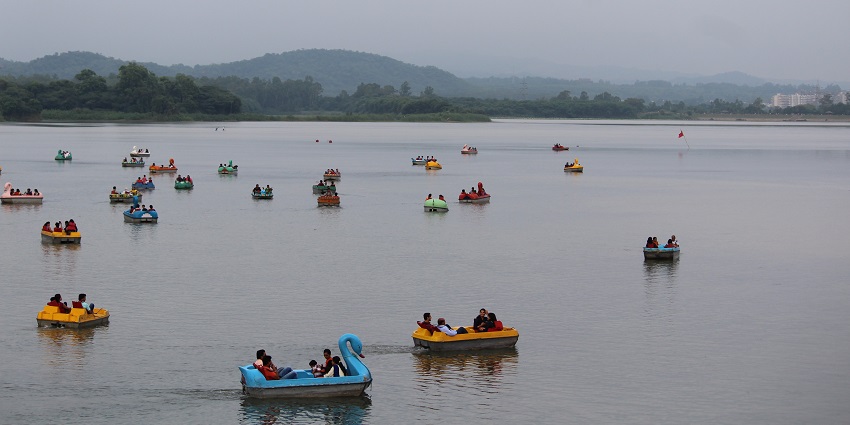 A breathtaking view of a lake in Haryana with people enjoying boating during the day.