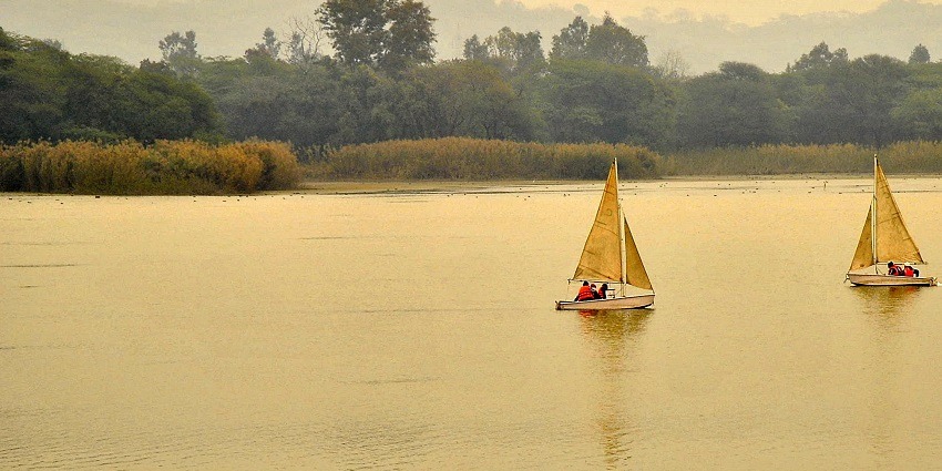 Sukhna Lake in Chandigarh, surrounded by greenery, with a tranquil surface - Places To Visit Near Panchkula