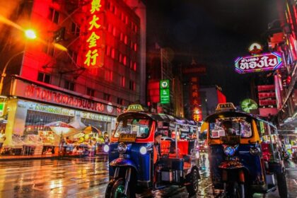 An image of two tuk-tuks in Bangkok’s Chinatown and neon lights in the background.