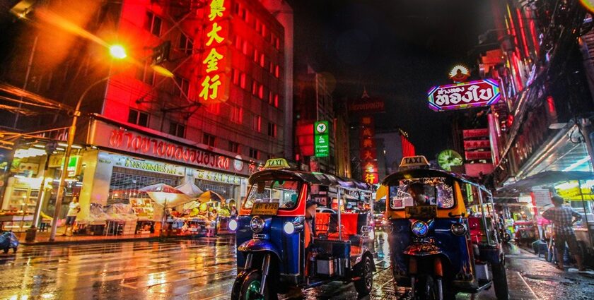 An image of two tuk-tuks in Bangkok’s Chinatown and neon lights in the background.