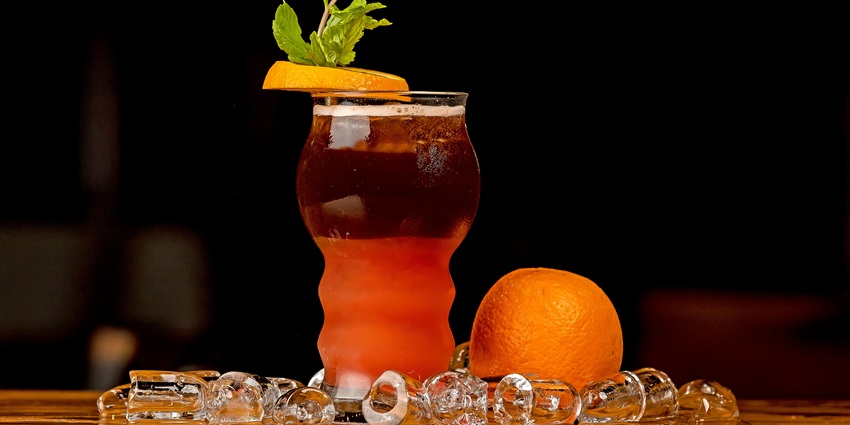 A picture of a bartender preparing a cocktail and dressing it with lime at a bar