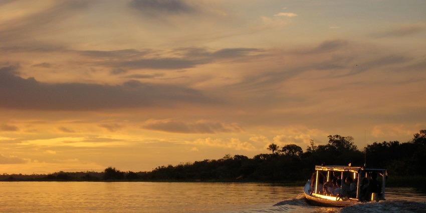 A picture of people taking a boat ride in Udaipur lake during the time of sunset