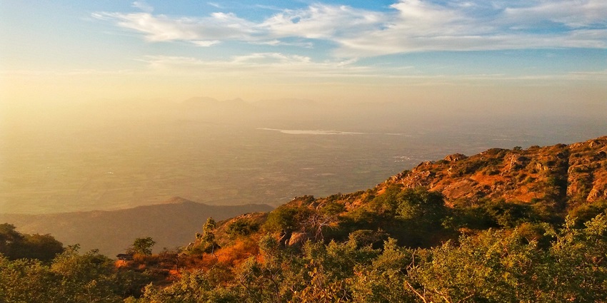 Stunning sunset at a little distance from Mount Abu, with the sun setting behind distant hills and casting a warm golden hue across the sky.