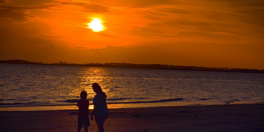 A serene beach at sunset, with vibrant colors reflecting on the water and soft waves.