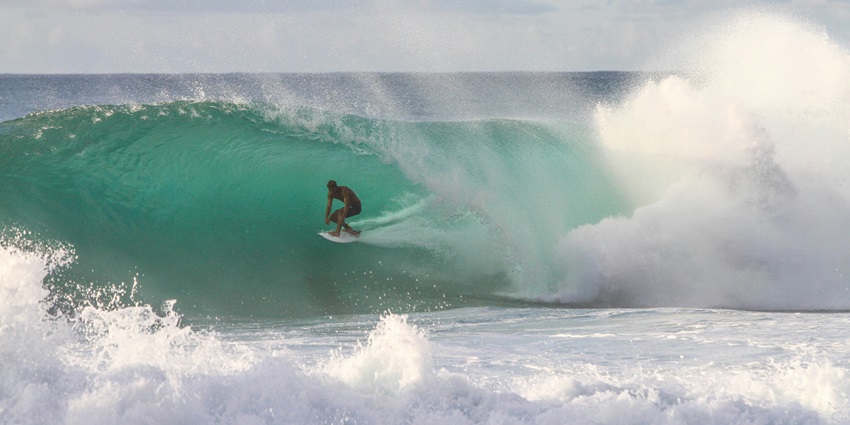 A fascinating view of a person enjoying surfing at Anjuna Beach during the daytime.