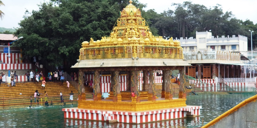 A view of a temple nestled amidst the shimmering waters of Swami Pushkarini Lake.
