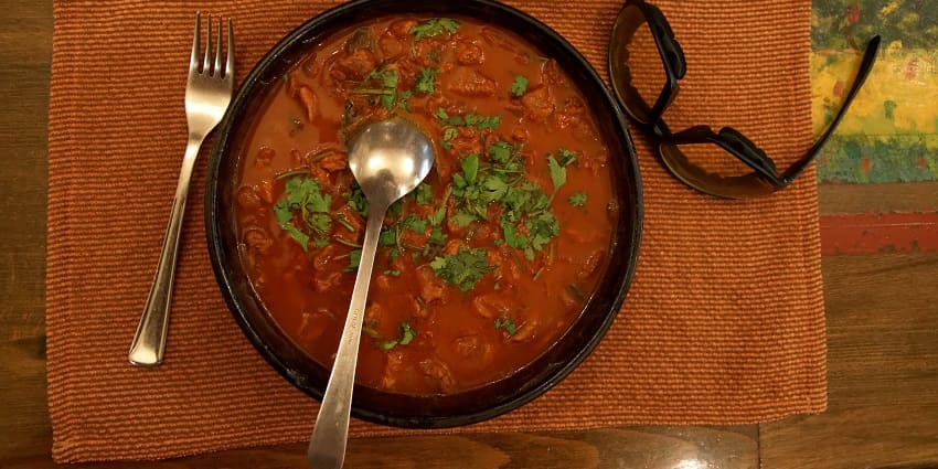 A mutton curry served in a bowl, featuring tender meat in a rich, spicy sauce, representing some of the best food in Bhuj.