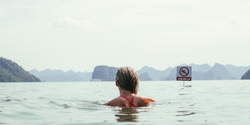 A tourist captured in a photo while enjoying swimming activity at waterfalls.