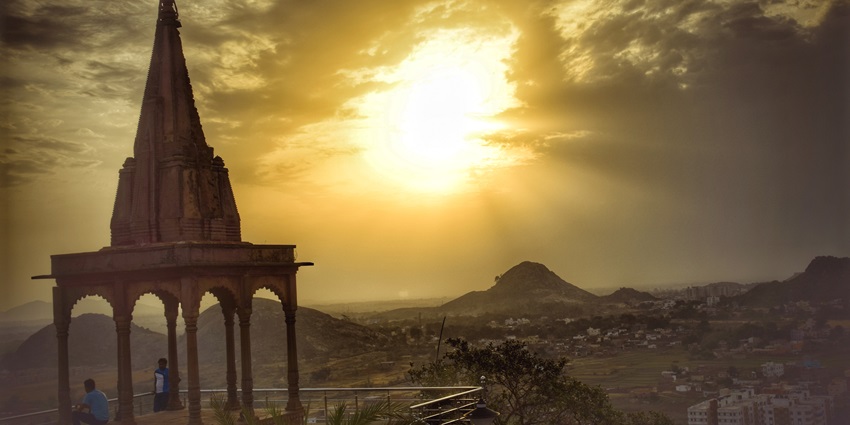 Landscape of Tagore Hill surrounded by forest and glowing in sunlight with two people