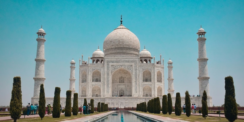 Majestic Taj Mahal, a white marble mausoleum, surrounded by lush gardens and reflecting pools.