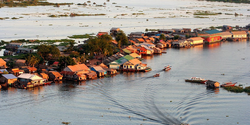 Aerial view of the serene waters of Tonle Sap Lake, with traditional scenery in the background