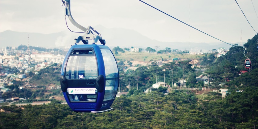 A picture of a cable car moving across the lush green hills of Da Lat