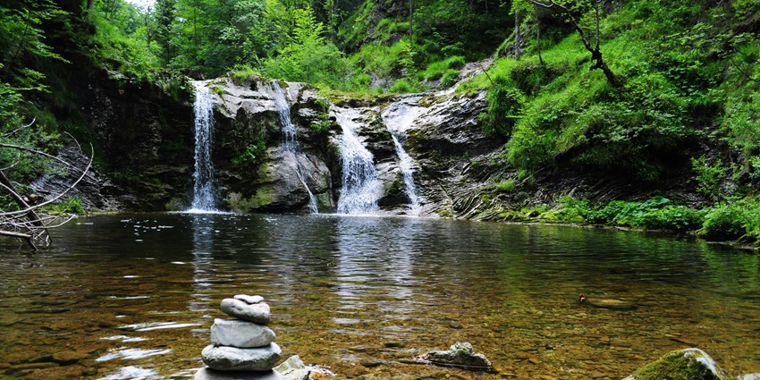 Tanda Falls cascades amidst lush dense greenery, offering a stunning waterfall view.