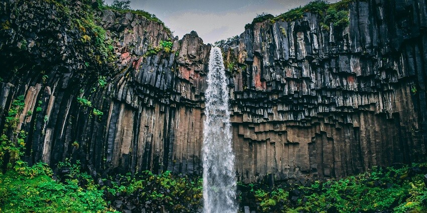 Tanda Falls cascades amidst lush dense greenery, offering a stunning waterfall view.