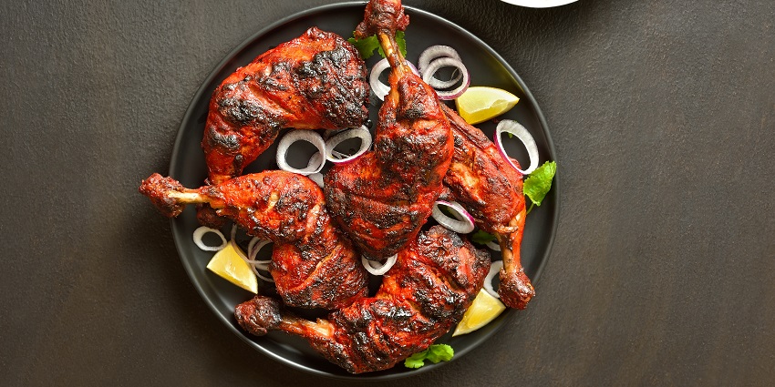 Tandoori chicken garnished with onions, lemon slices and coriander