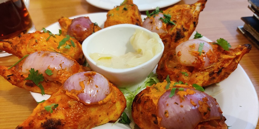 Tandori momos served with mint chutney garnished with onions and coriander