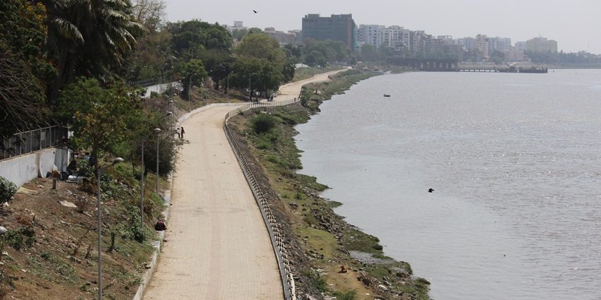 View of the Tapi Riverfront road, lined with trees and providing scenic riverside access.