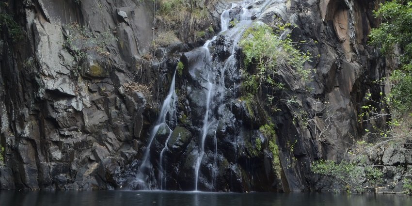 A picture of water cascading down a tall hill into a water body