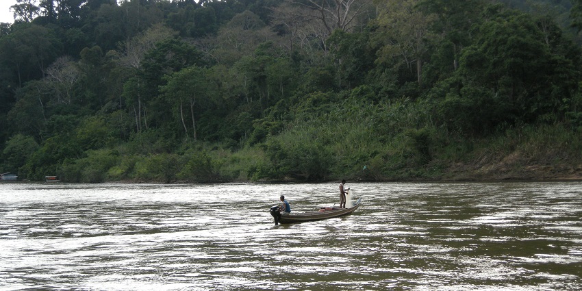 Image of person fishing in a small boat on the calm waters of Tembeling River, Taman Negara.