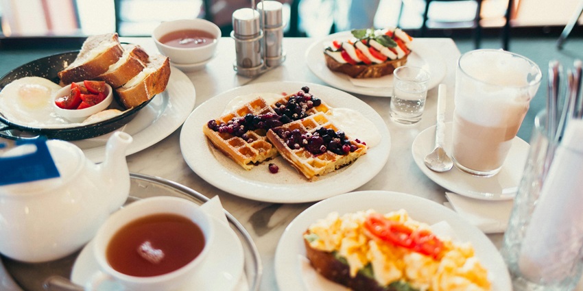 A picture showing a restaurant table served with a proper French buffet including waffles and toasts