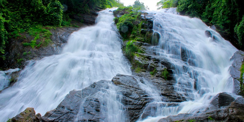 A stunning waterfall cascades down rocky cliffs, surrounded by lush greenery
