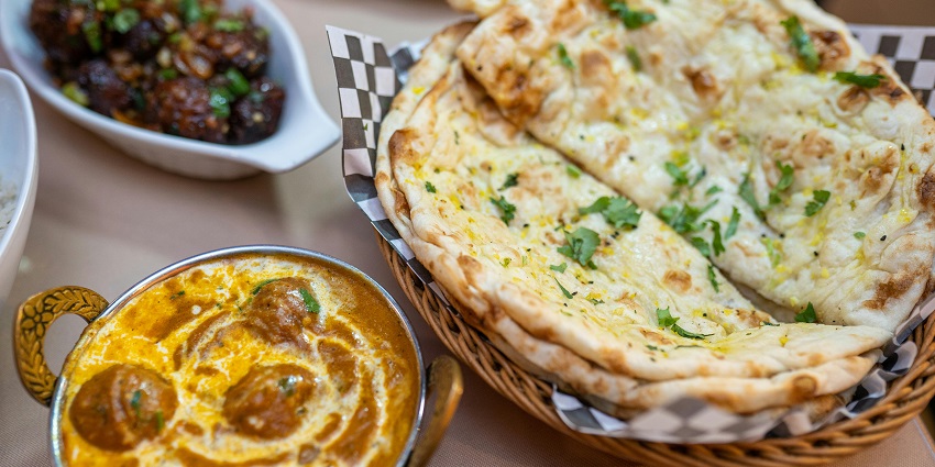 A naan and roti served with butter chicken, a popular North Indian meal