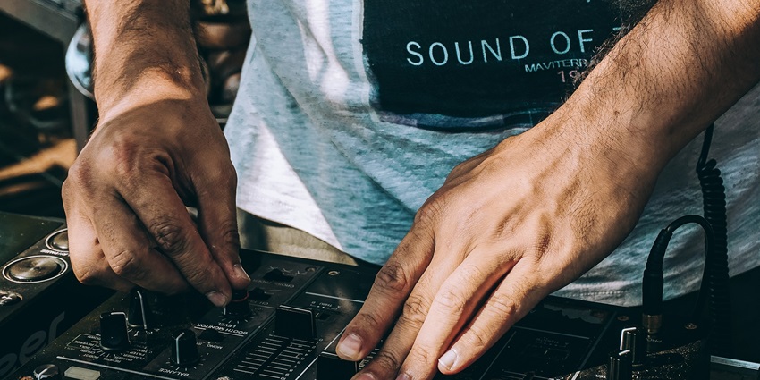 DJ adjusting the mixer to set the perfect vibe for a nightclub party for all to enjoy.