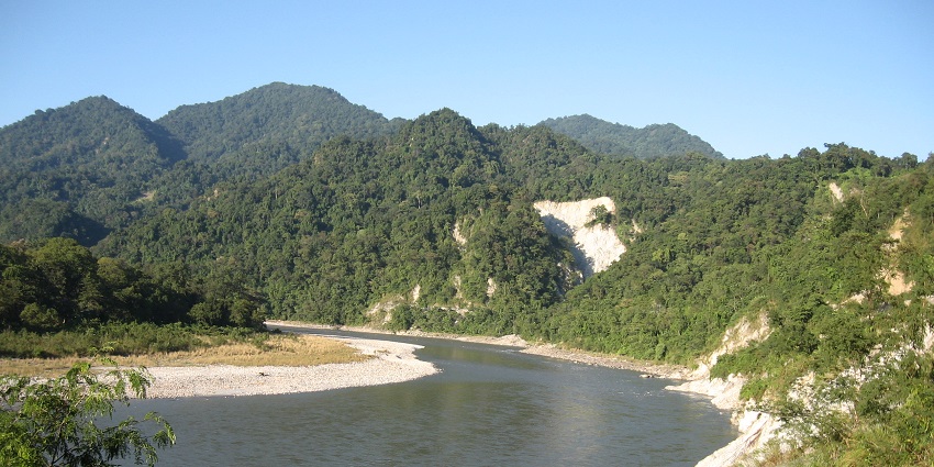 Manas River flowing through Royal Manas National Park, flanked by dense greenery.