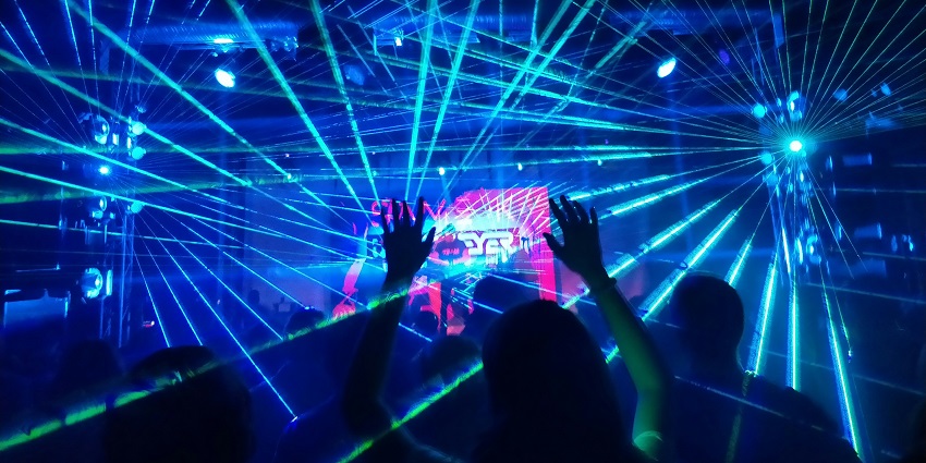 A glimpse of people dancing amidst bright neon lights at the Royal Melange Hotel.