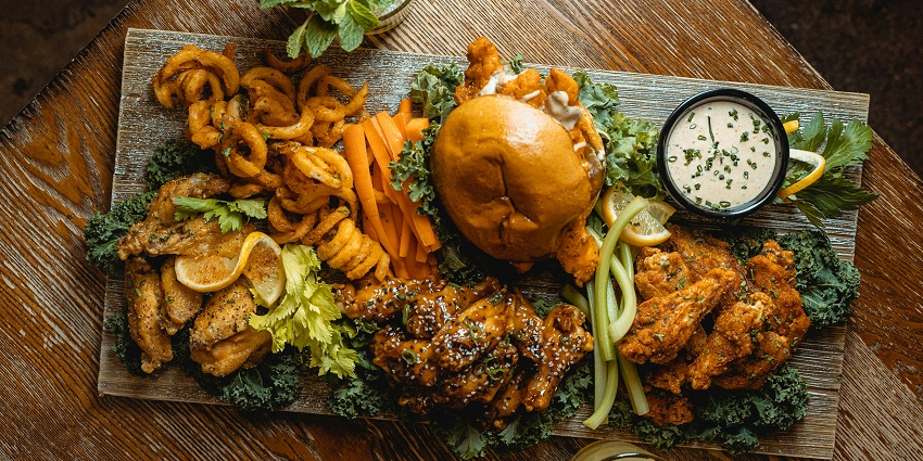A platter with delicious burger, fries, and chicken, one of the best foods in Vadodra.