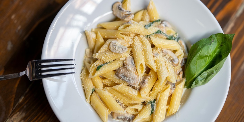 A plate of alfredo pasta served at the Secret Kitchen in Rajkot, having a cosy ambience
