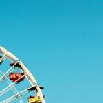 A glimpse of a giant ferris wheel with colourful seats in an adventure hub of the region.