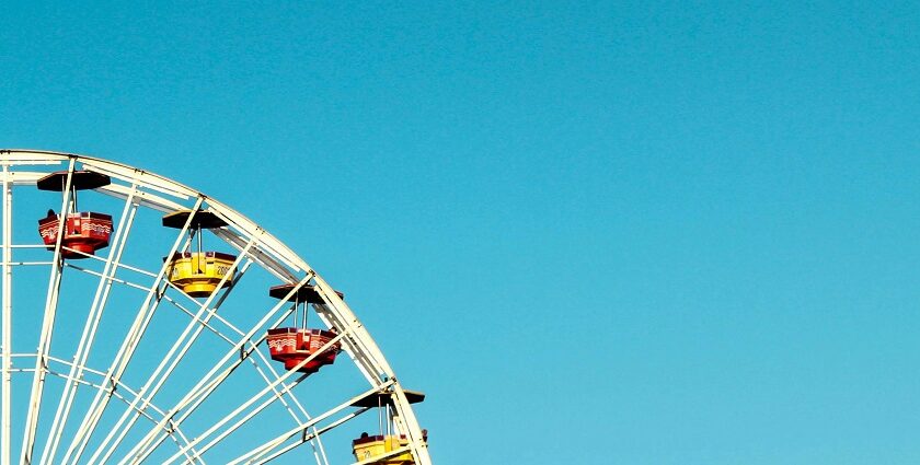 A glimpse of a giant ferris wheel with colourful seats in an adventure hub of the region.