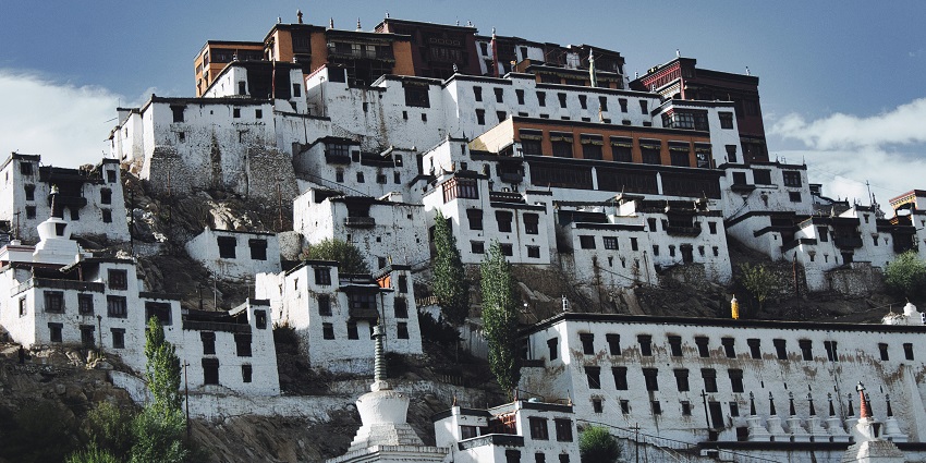 A fascinating view of the Thiksey Monastery surrounded by mountains during the day.